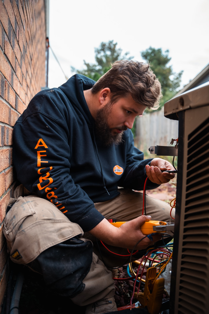 Rick's Affordable Heating & Cooling HVAC technician servicing an outdoor AC condenser unit in Toledo, Ohio