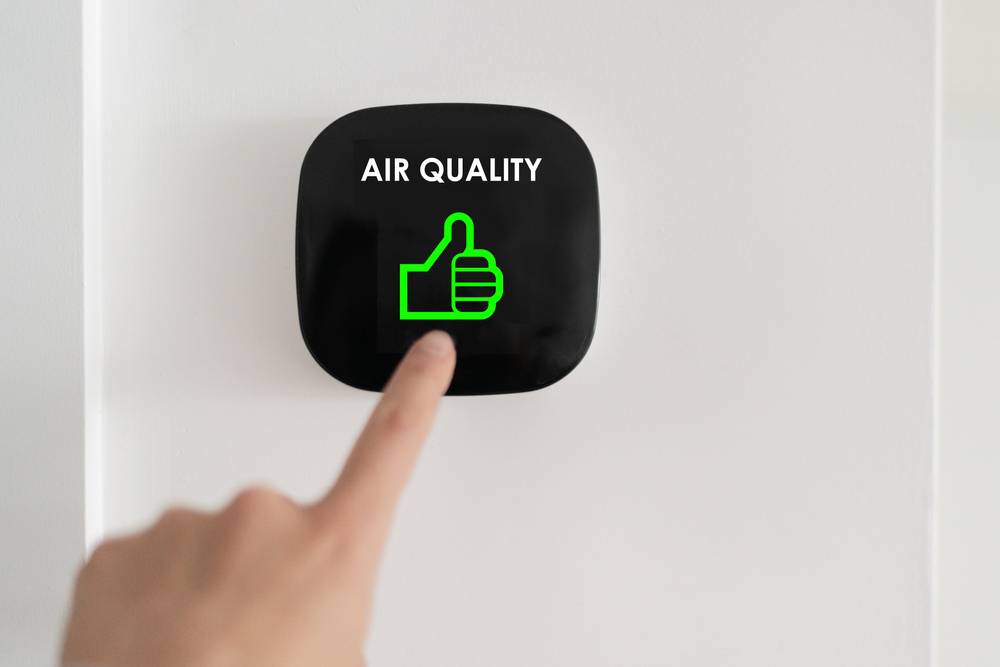 A finger pushing a button that says air quality