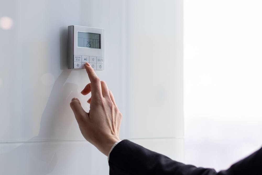 A woman's hand touching a thermostat