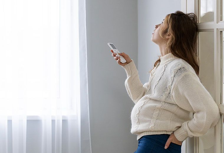 Pregnant woman by window, in need of an air conditioning replacement in Perrysburg, OH