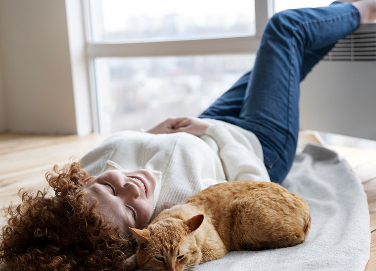 Woman lays cozy with cat after duct cleaning by Ricks Affordable Heating and Cooling in Perrysburg, OH
