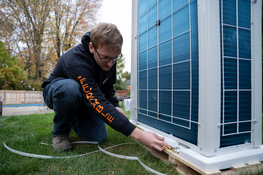 Rick's Affordable technician measuring a new AC unit during replacement installation