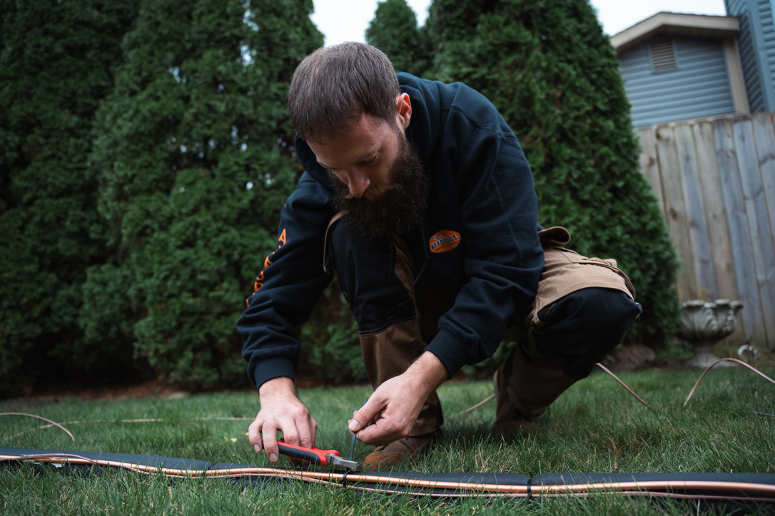 Rick's Affordable technician cutting copper refrigerant line set for heat pump installation