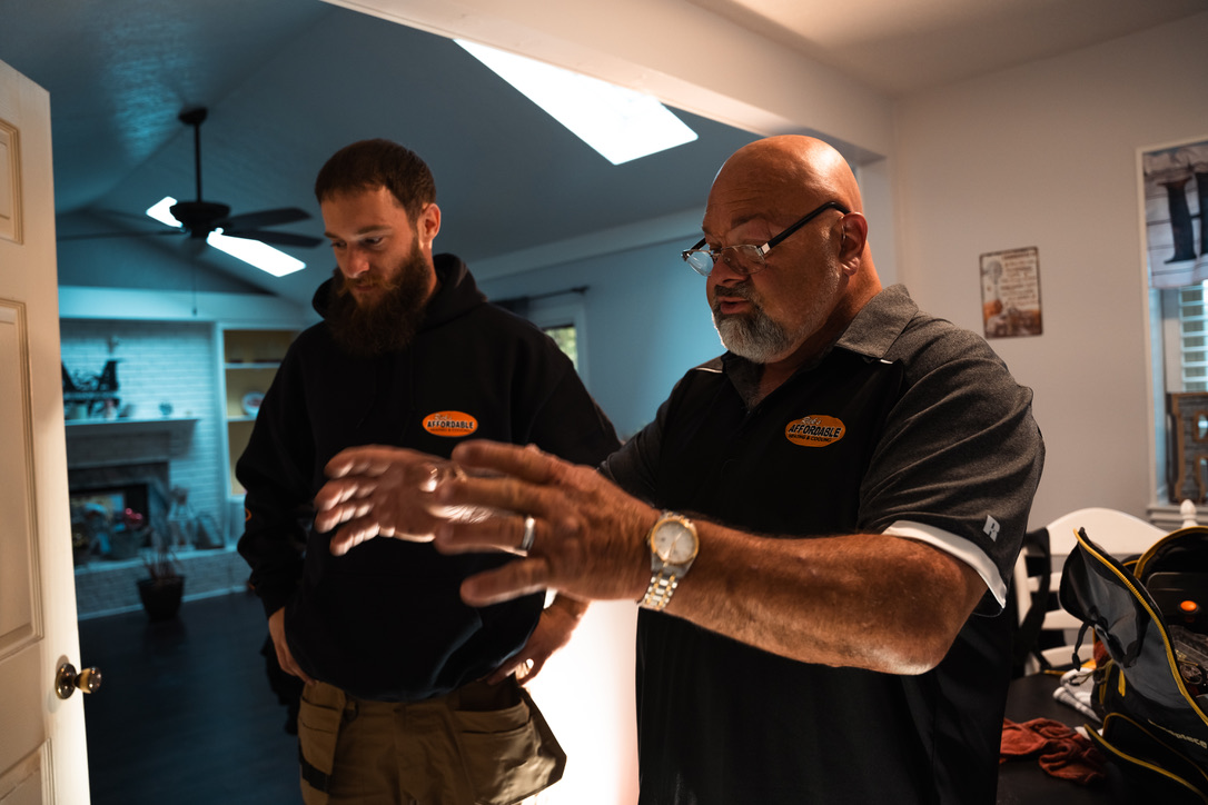 Rick's Affordable Heating & Cooling owner consulting with technician inside a customer's home