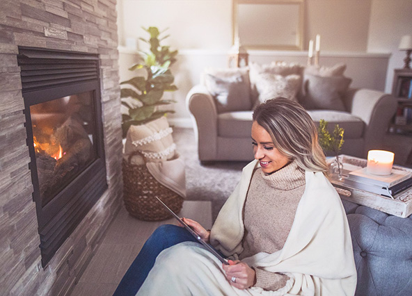 Woman sitting cozy by fireplace installed by Ricks Affordable Heating and Cooling in Perrysburg, Ohio