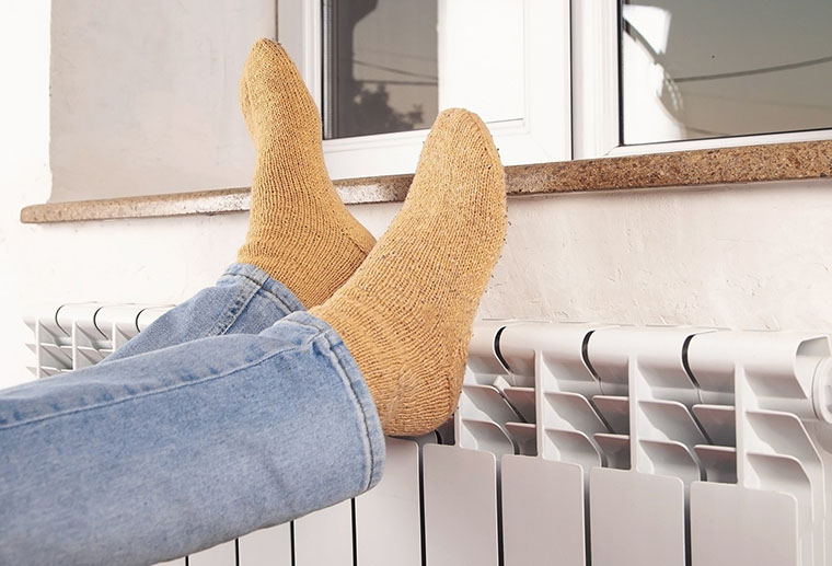 Women warming feet by radiator after heat pump repair in Perrysburg, OH