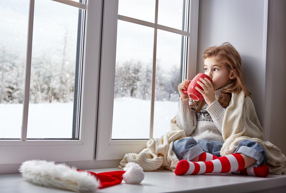 A little girl sitting in her cozy house, drinking hot chocolate