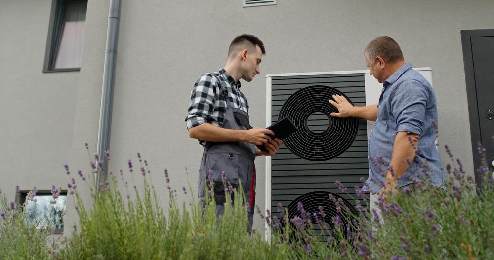 A homeowner and a technician looking at a heat pump.