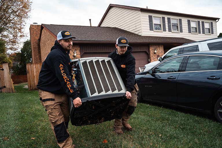 Technicians from Rick's Affordable Heating and Cooling in Toledo, OH carry old HVAC unit